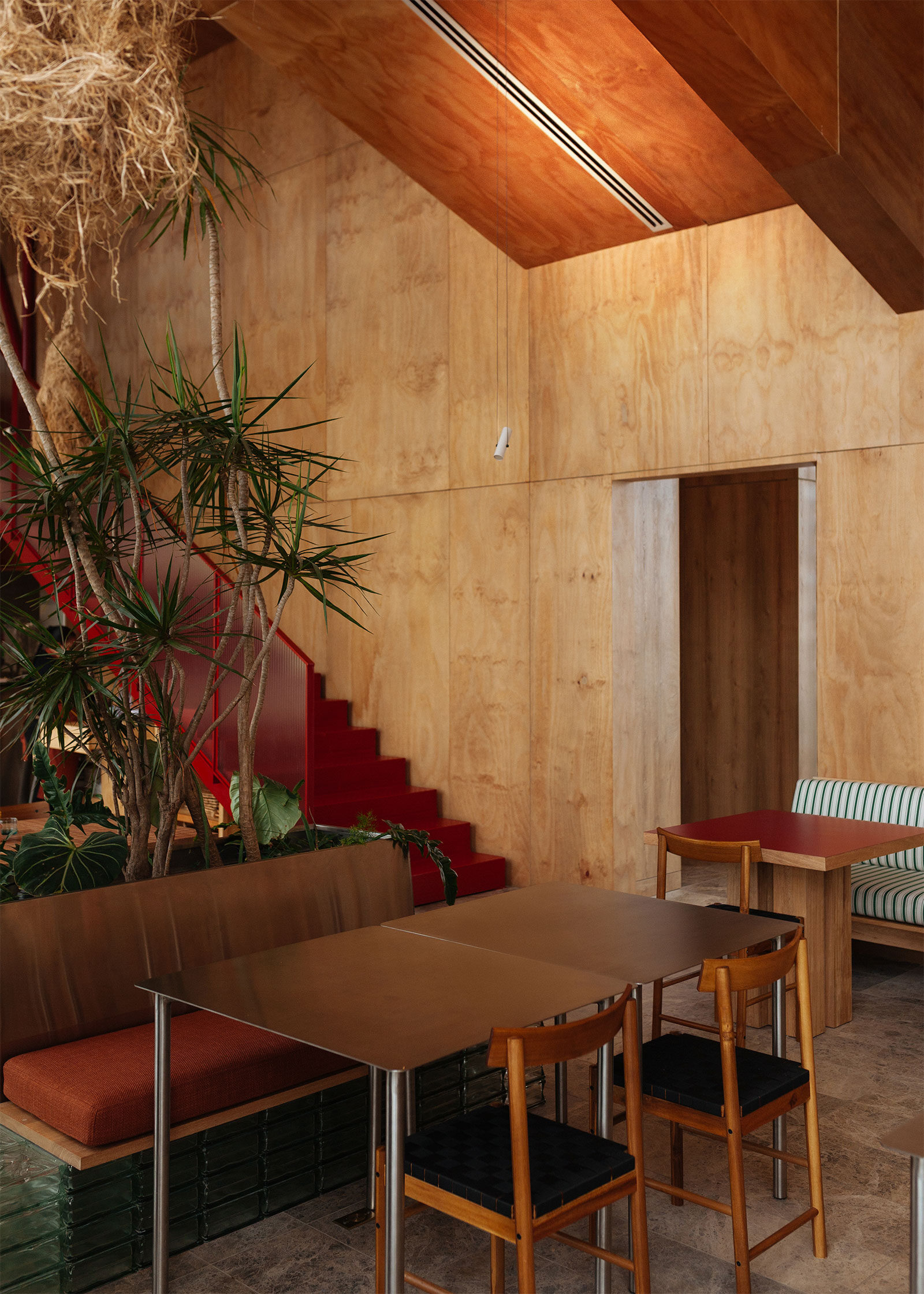 Interior al restaurantului Silo, Medellín, cu lemn, scară roșie și separeuri