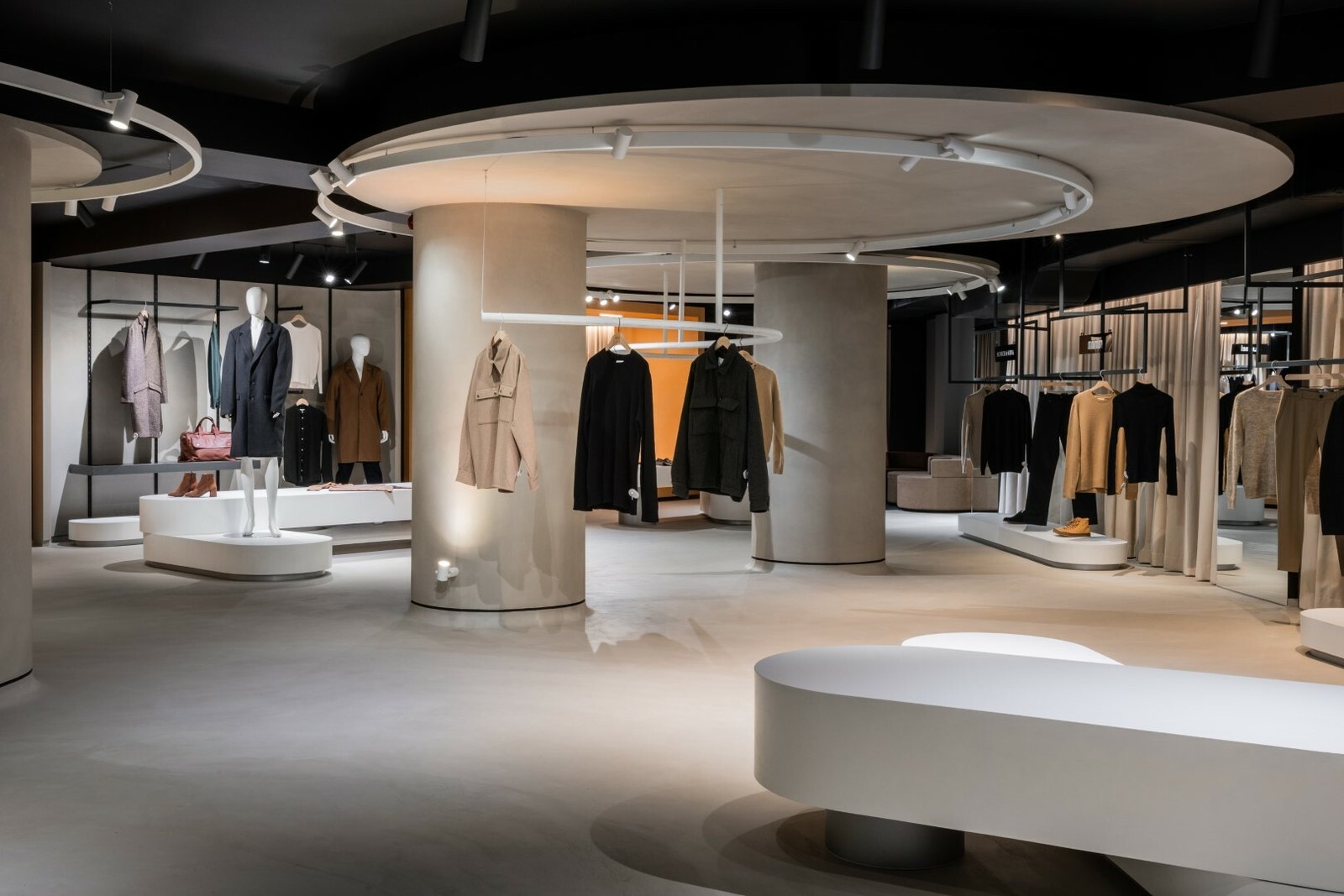 Sala principală a boutique-ului Brothers din Chișinău, cu inel de lumină suspendat peste coloana centrală, proiectoare pe șină și rafturi cu haine
